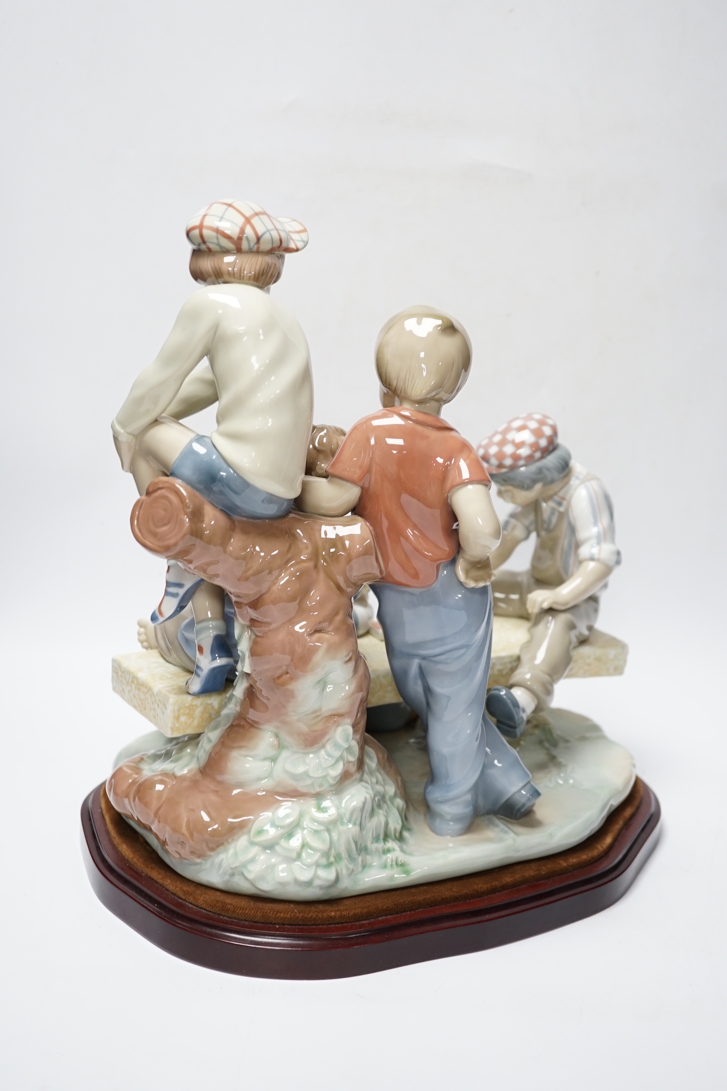 A large Nao figure group on stand of five boys sitting around a table playing cards, 33cm